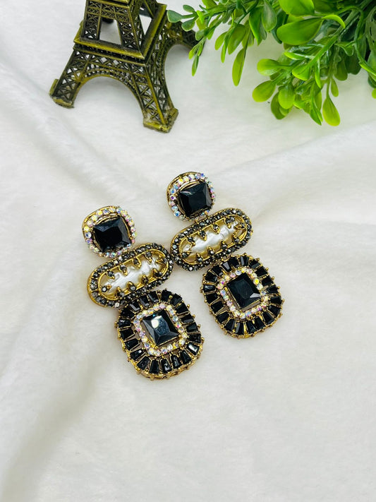 Ornate earrings with black and gold details on a white surface.