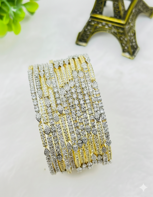 Gold and silver bracelet on a white surface with a decorative Eiffel Tower object in the background.