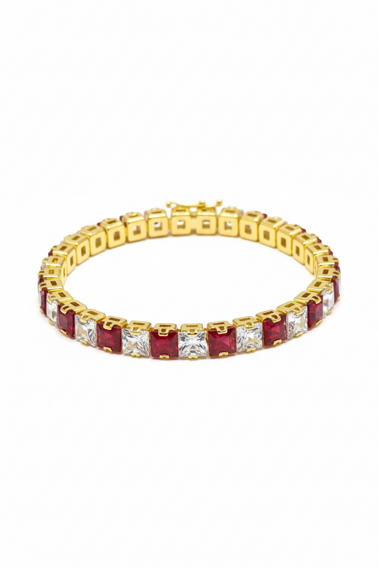 Gold bracelet with red and clear gemstones on a white background