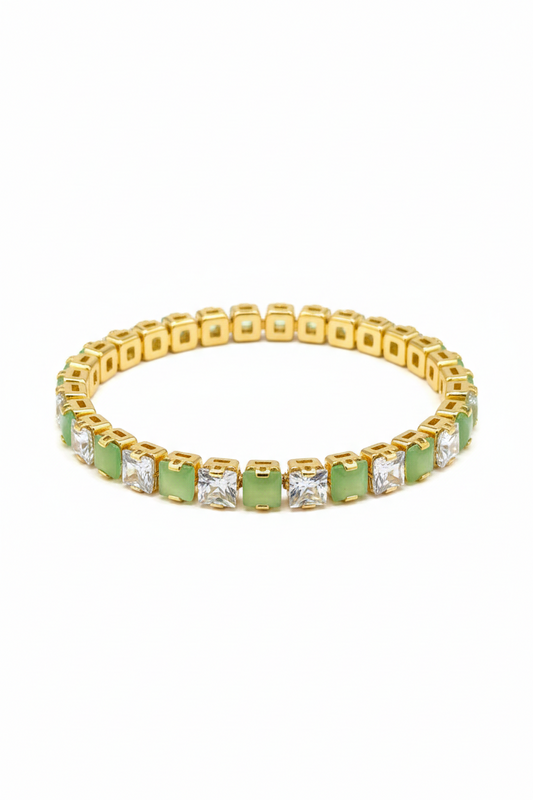 Gold bracelet with green gemstones on a white background