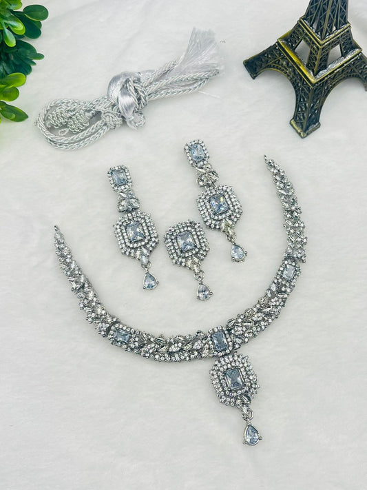 Silver necklace and earrings with blue stones on a light surface with decorative items.