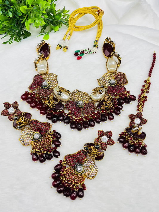 Ornate necklace set with maroon and gold colors on a white background